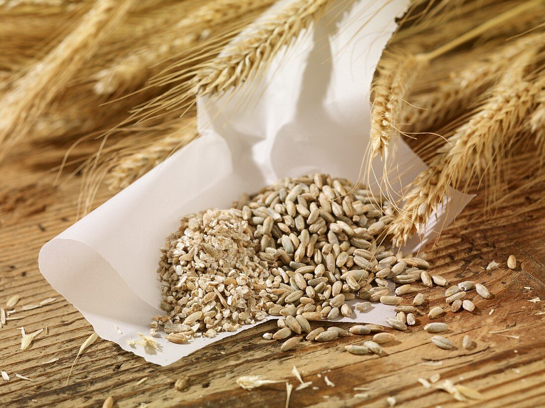 Rye seeds, groats and ears of rye on a wooden surface