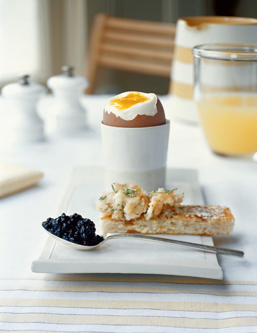 A soft boiled egg and a slice of toast with smoked salmon and caviar