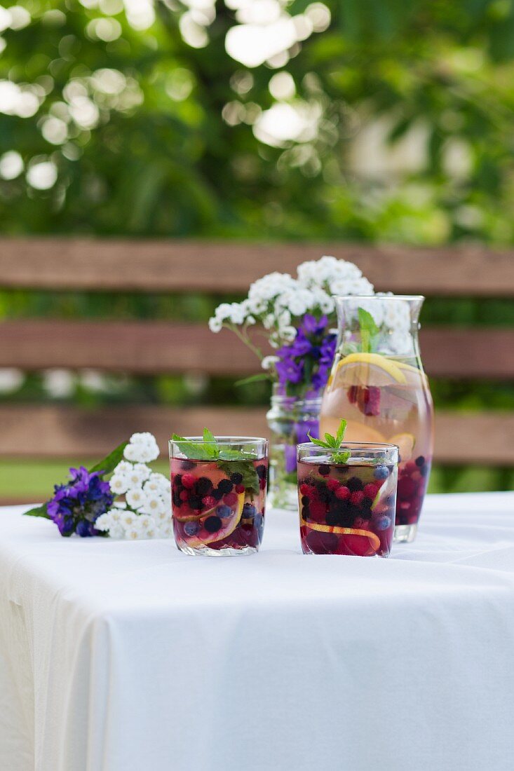 White wine sangria with summer fruits on a garden table