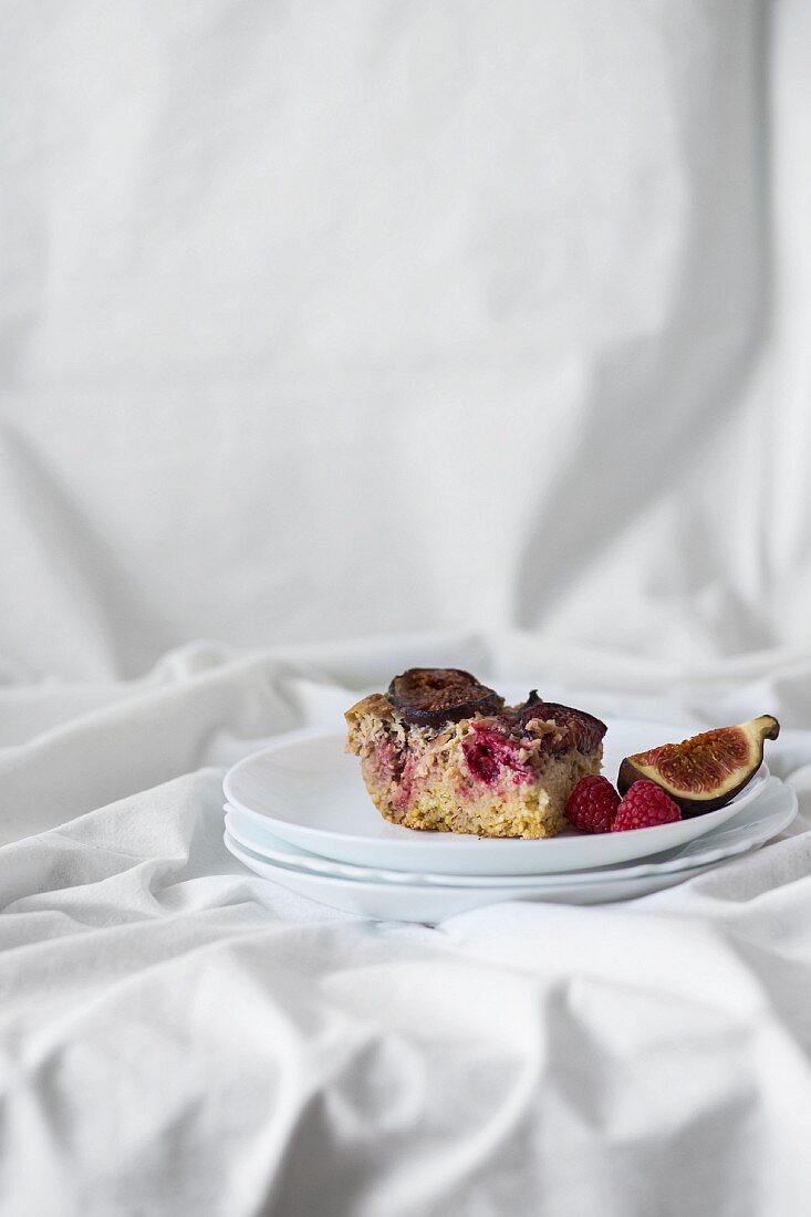 A slice of millet cake with figs, raspberries and nuts