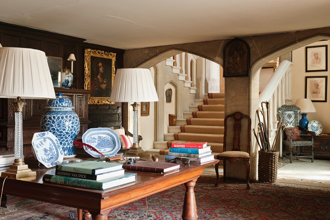 Jacobean manor house with stone Tudor arches, Chinese lidded jars, plates and lamps with crystal bases on mahogany table in foyer