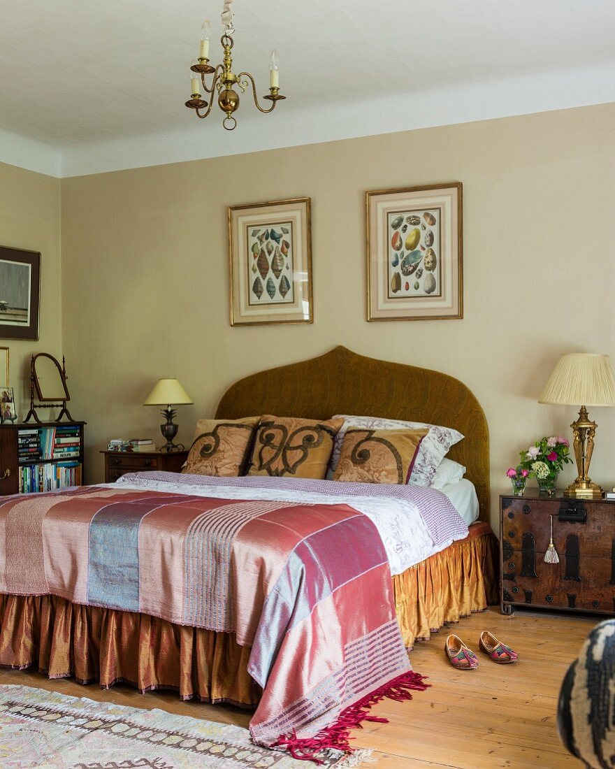 Elegantes Doppelbett mit geschwungenem Kopfteil und Seidendecke in traditionellem Schlafzimmer