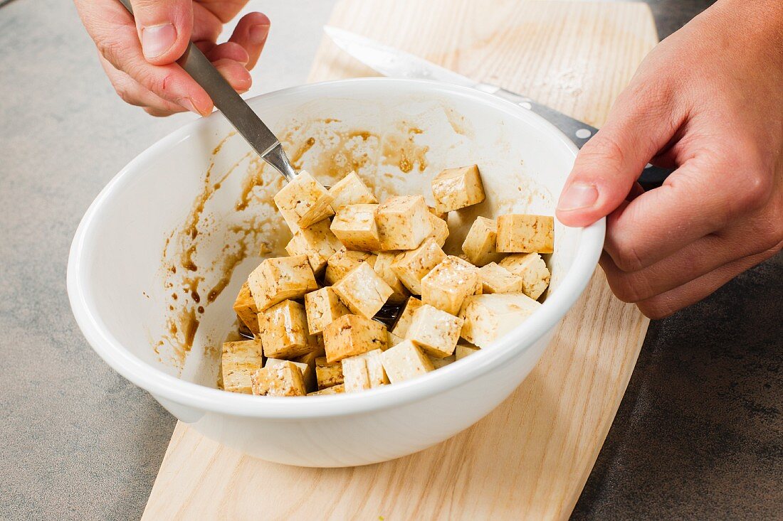 Tofuwürfel mit Sojasauce und Sesamöl marinieren