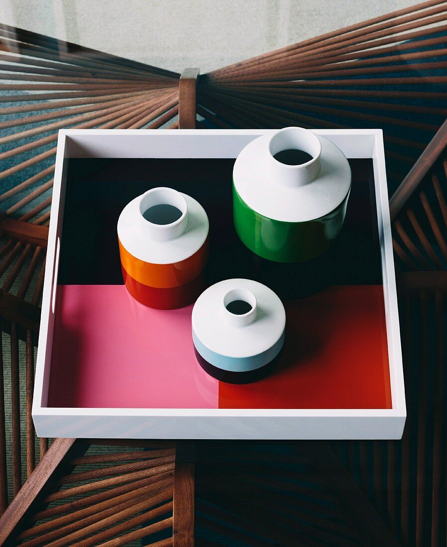 Vases and trays in retro colors on a glass table with a handcrafted wooden frame