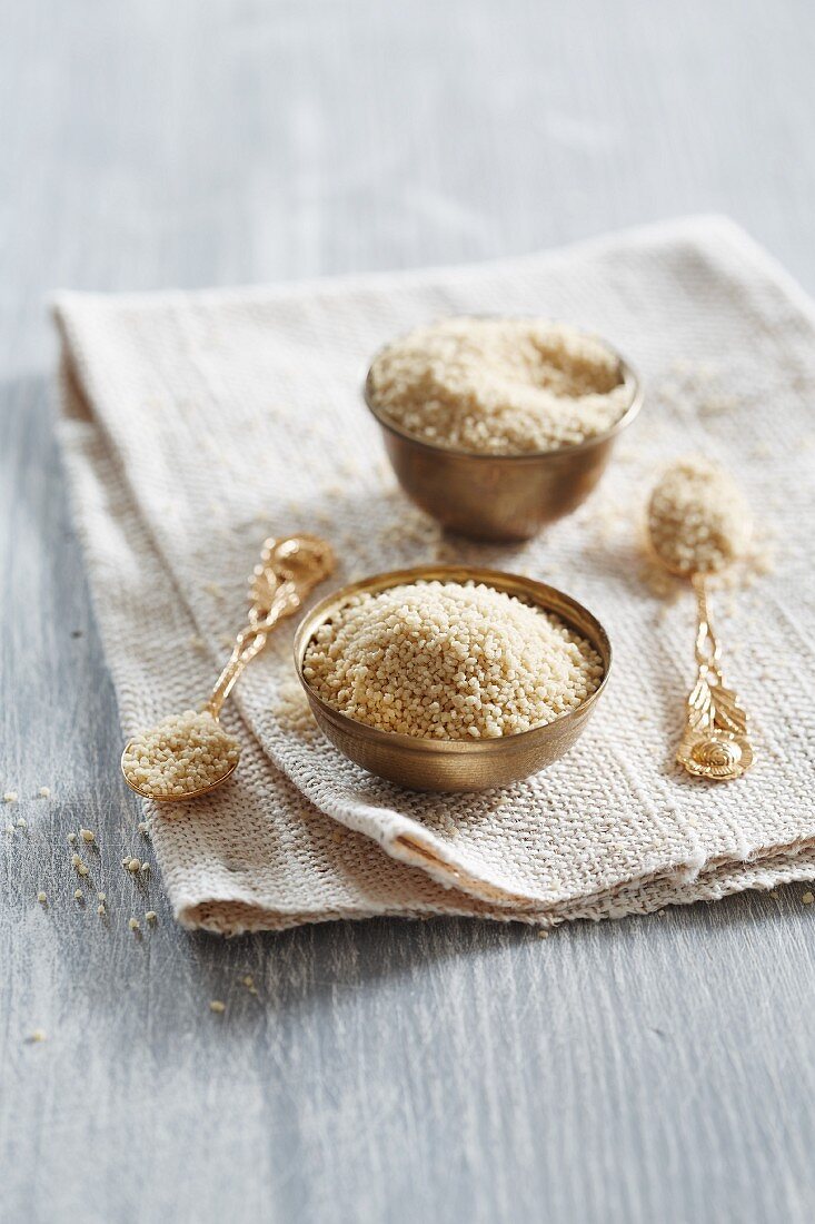 Couscous in metal bowls and on spoons