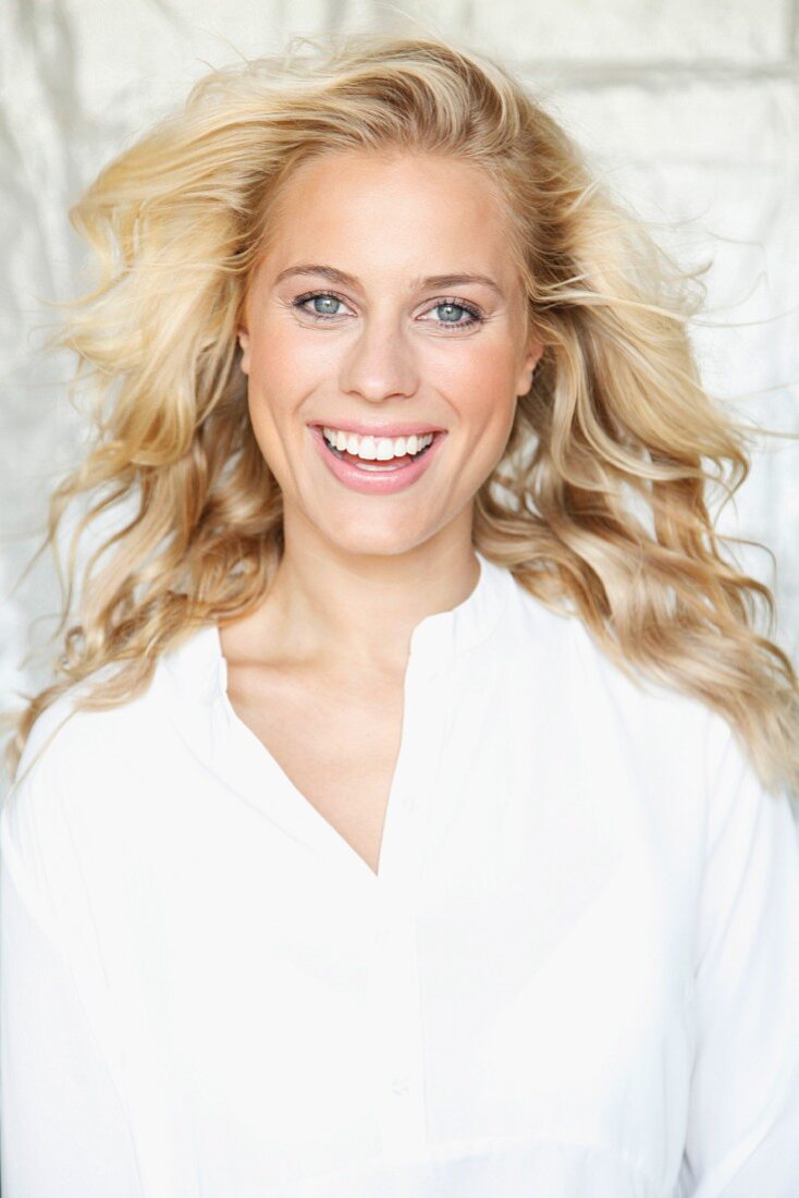 A laughing blonde woman wearing a white blouse