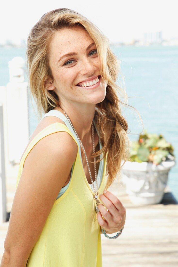 A blonde woman wearing a light yellow top and a fashionable necklace