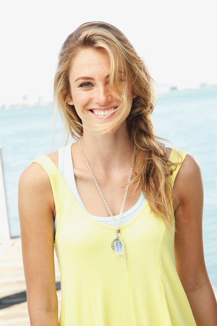 A blonde woman wearing a light yellow top and fashionable necklace