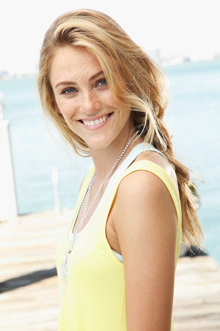 A blonde woman wearing a light yellow top and a fashionable necklace