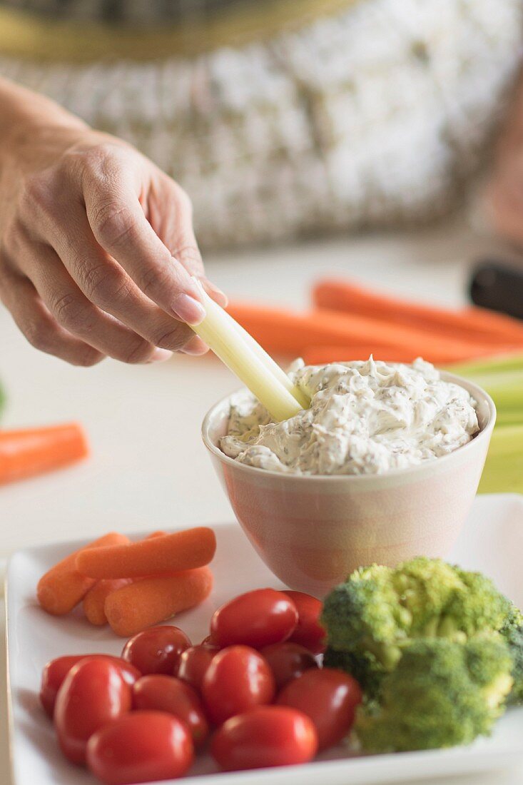 A woman preparing vegetables and a dip