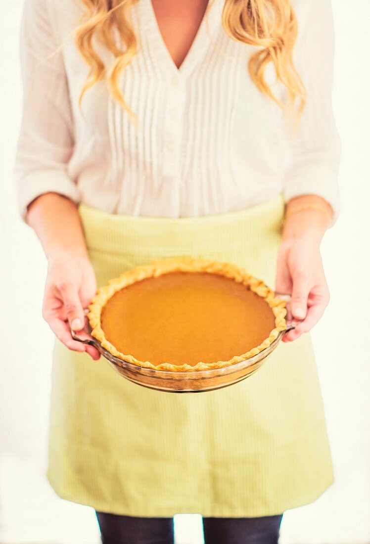 A woman holding a pumpkin pie