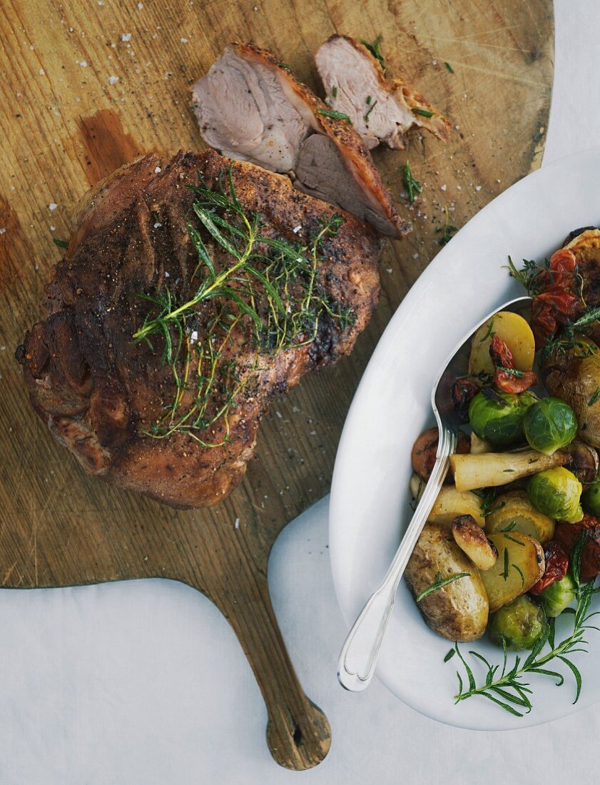 Lammkeule mit Kartoffeln und Rosenkohl auf grossem Holzbrett