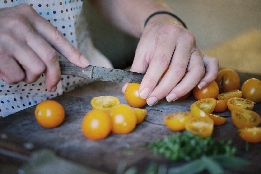Frau halbiert kleine gelbe Tomaten