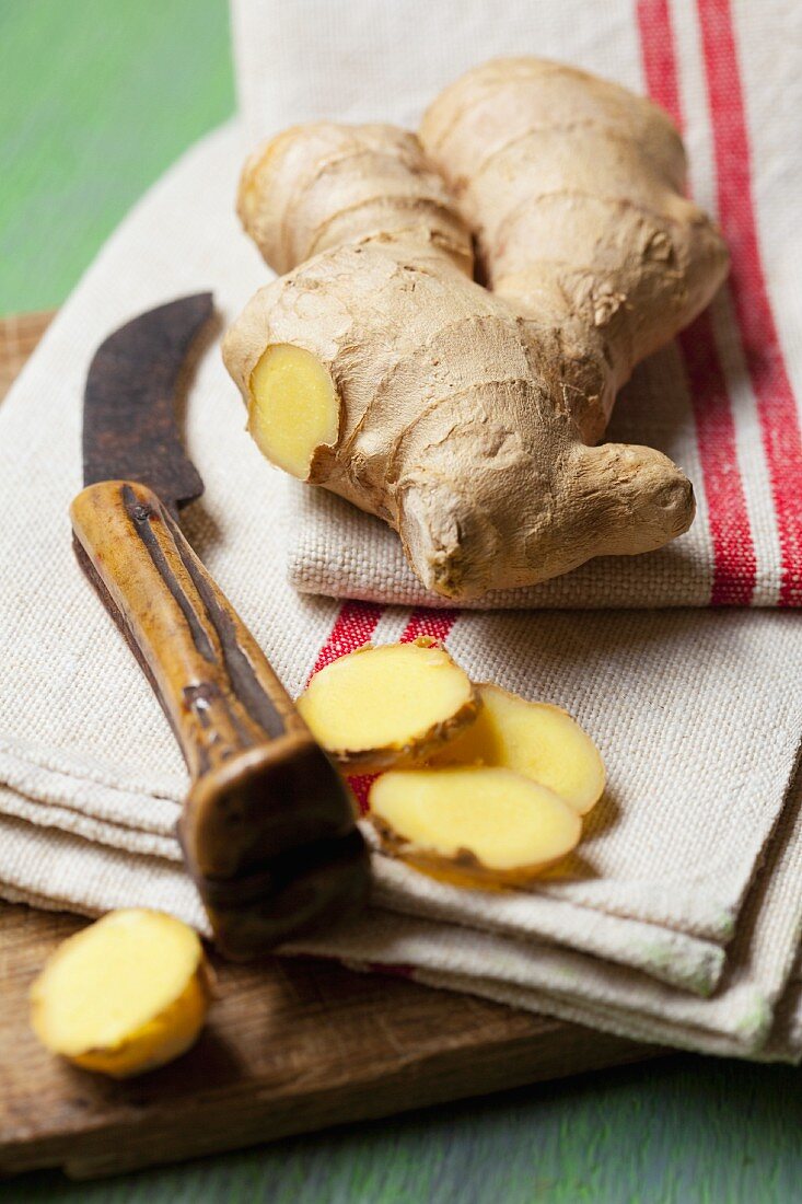 Fresh ginger on a tea towel with a knife