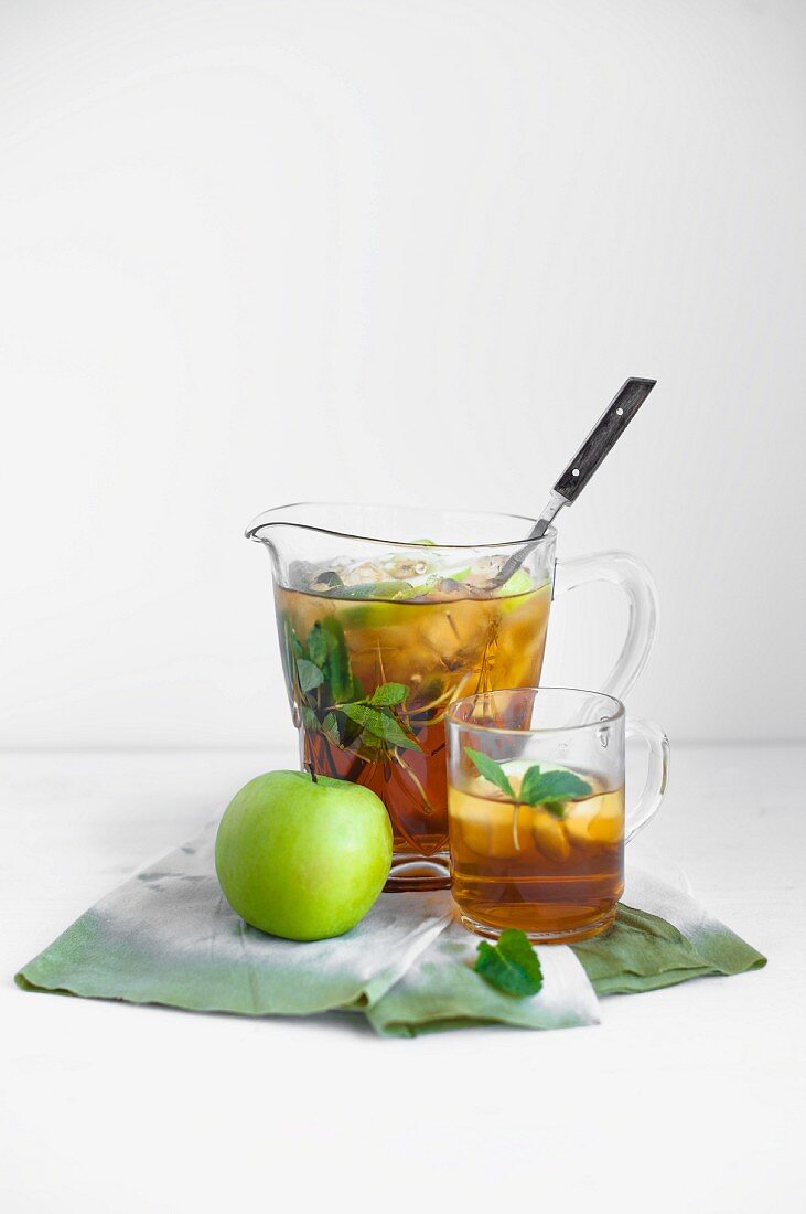 Apple and mint iced tea in a glass and in a jug