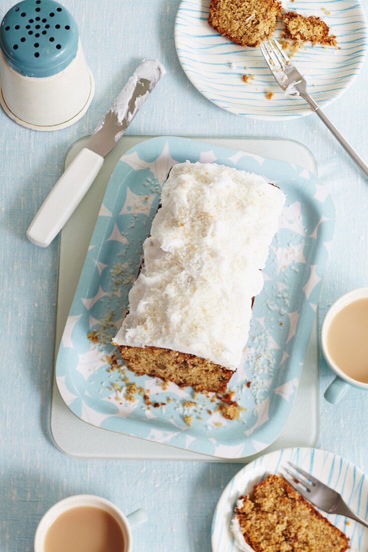 Walnut loaf cake with frosting and grated coconut, sliced