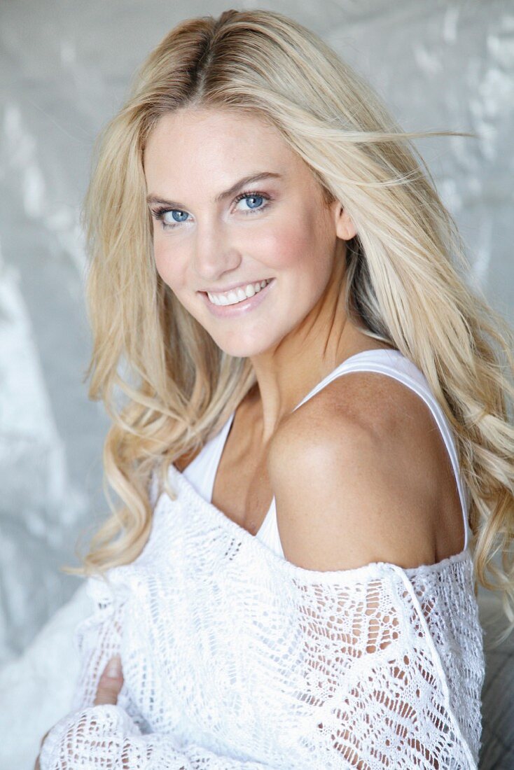 Young blonde woman in white top and lacy sweater