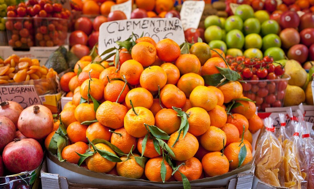 Clementines, pomegranates, tomatoes, apples, dried apricots and dried mango at a vegetable stand in Venice, Italy