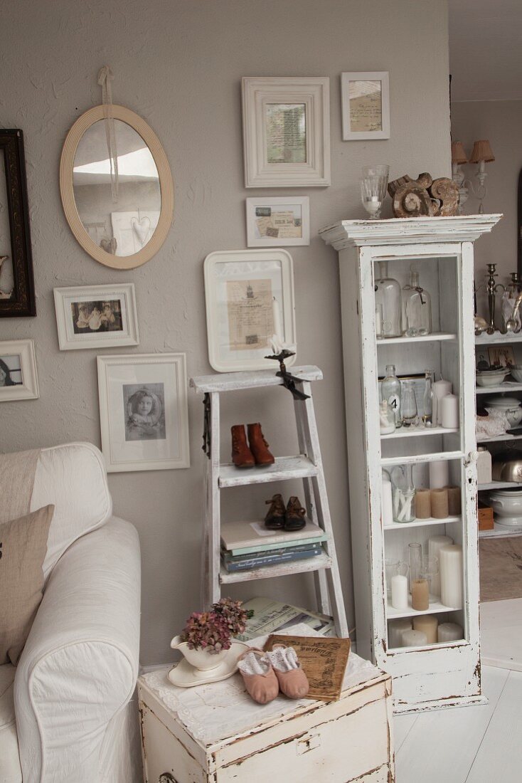 Shabby-chic occasional table below pictures hung on pastel wall