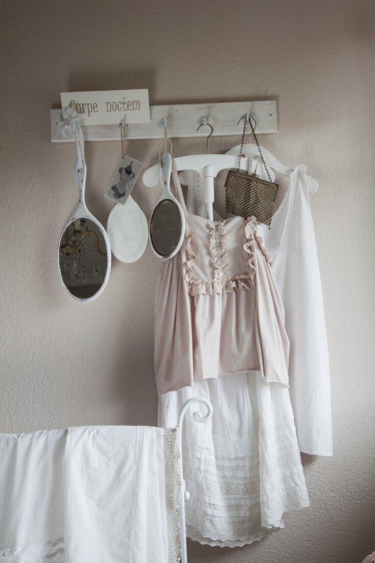 Vintage clothing and hand mirrors hanging from row of hooks