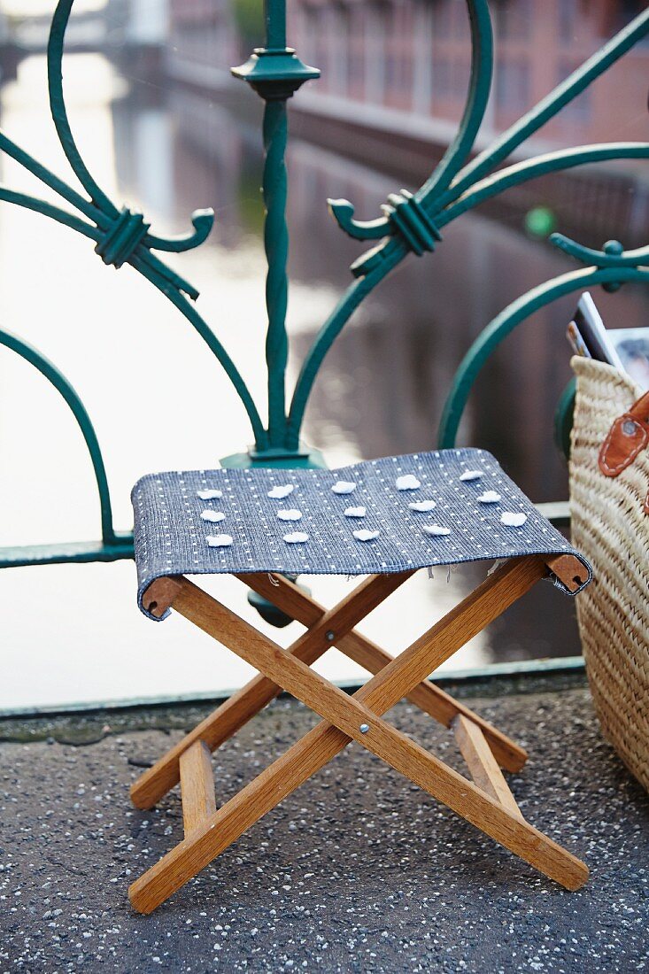 A folding wooden stool with a new fabric seat
