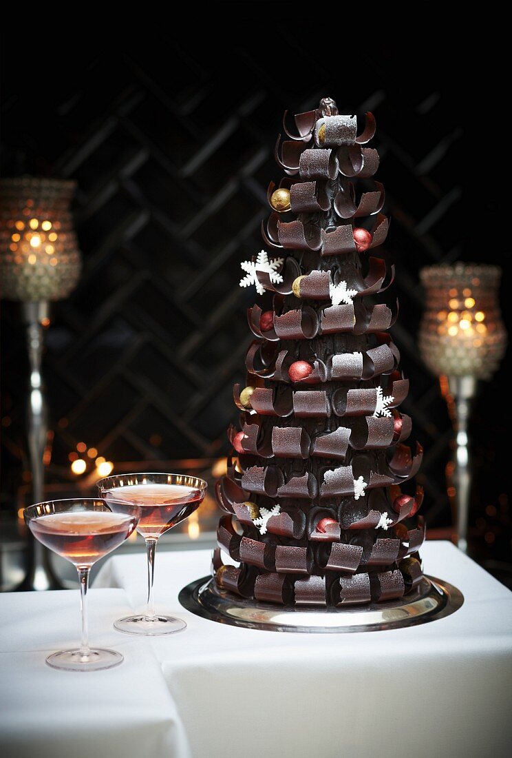 A table laid for Christmas with a Christmas tree sculpture made from chocolate curls with two glasses of rosé wine next to it
