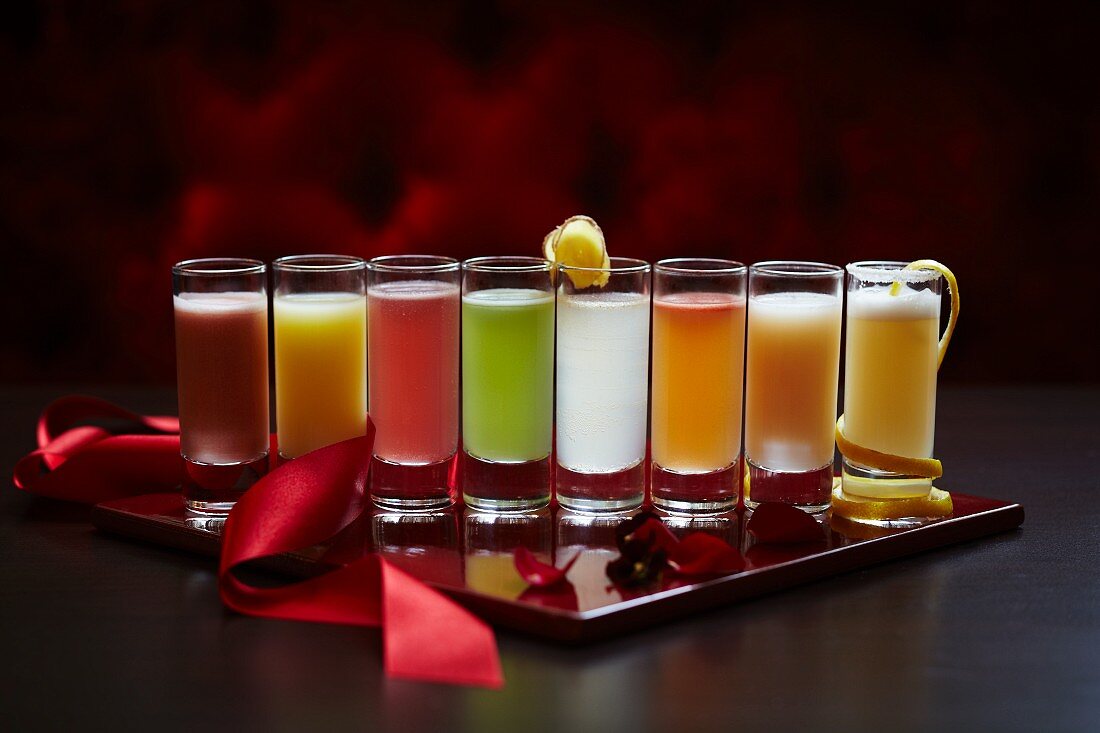 Eine Reihe Shotgläser mit verschiedenfarbigen Cocktails