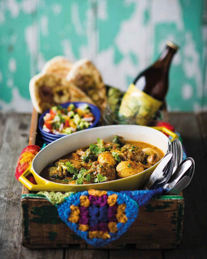 Lamb curry with vegetables, salads and unleavened bread on the side