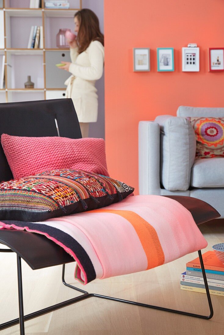 A living room with upholstered seats in black and grey complemented by a mixture of patterns in pink and coral
