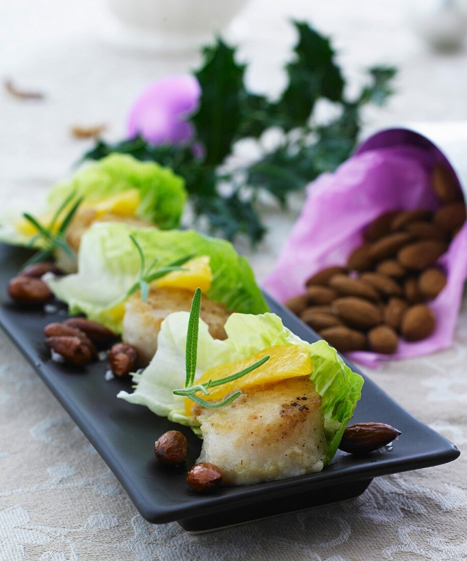 Scallops with orange fillets wrapped in lettuce leaves served with roasted almonds