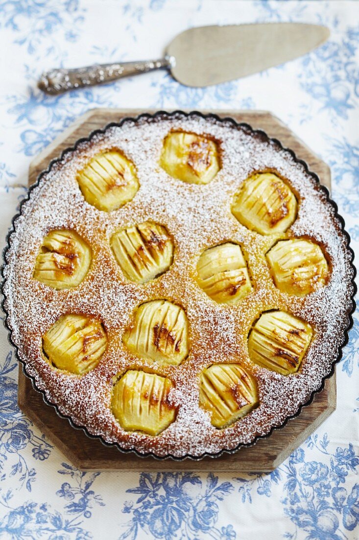 A large apple tart with whole apples and icing sugar