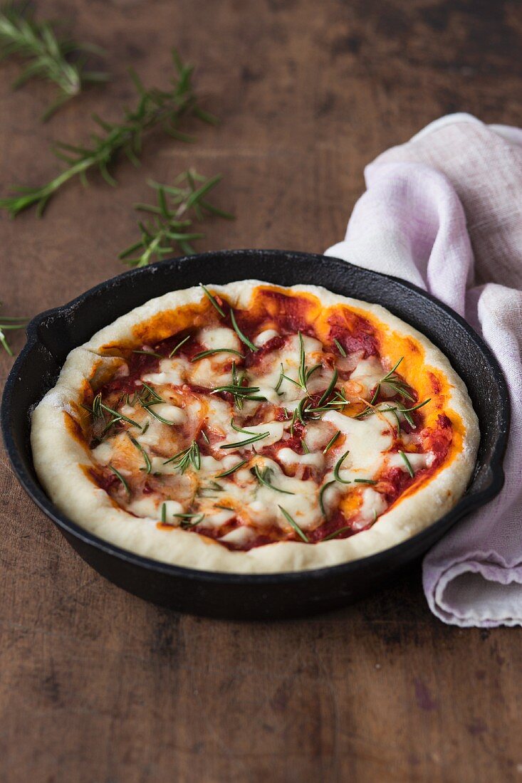Pizza Margherita with tomatoes, Mozzarella and rosemary in a rustic pan
