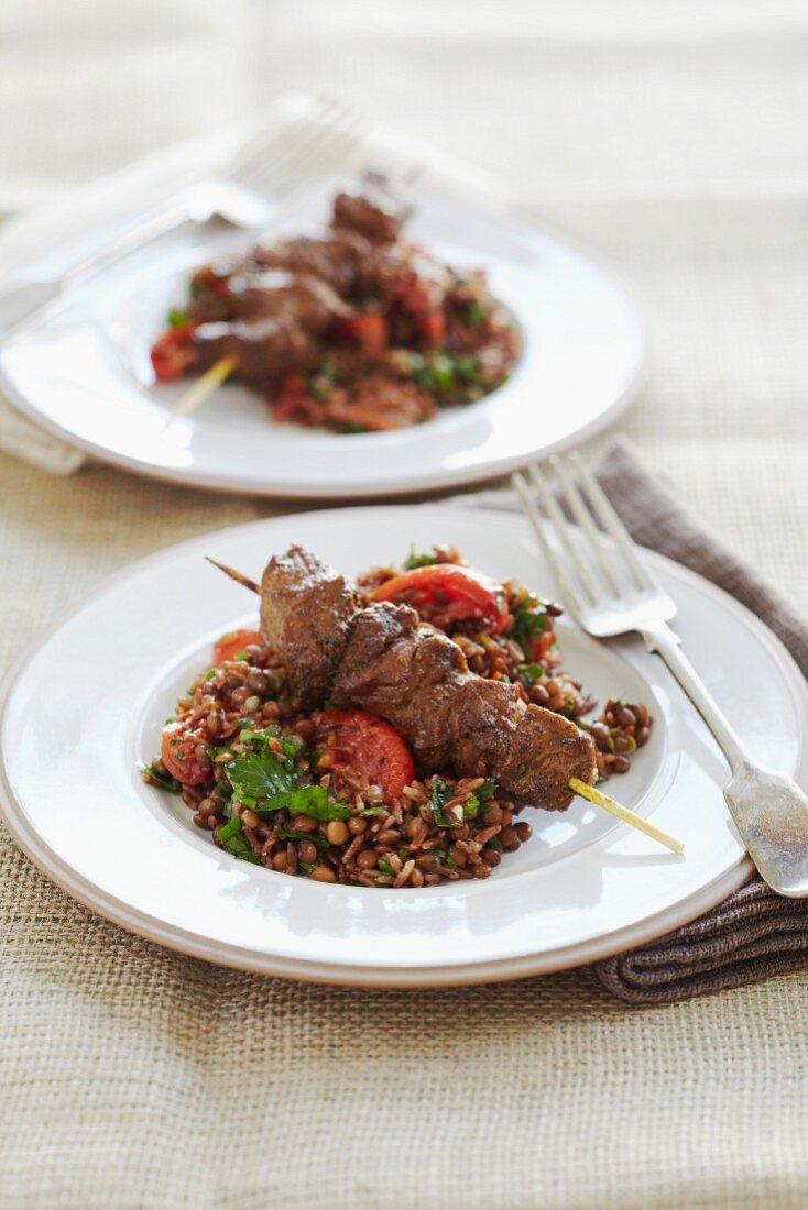Marinated lamb skewers with grilled tomatoes, rice and lentils