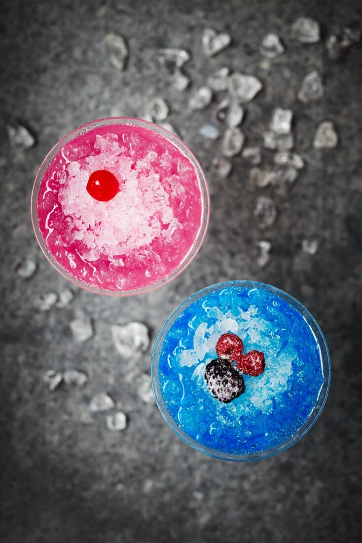 Frozen Cocktails in Hellblau und Rosa, garniert mit Beeren und Maraschinokirschen