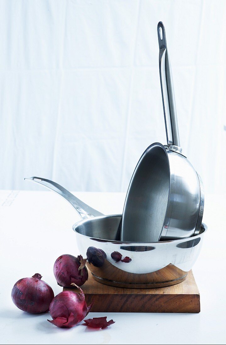 Stainless steel saucepans and red onions