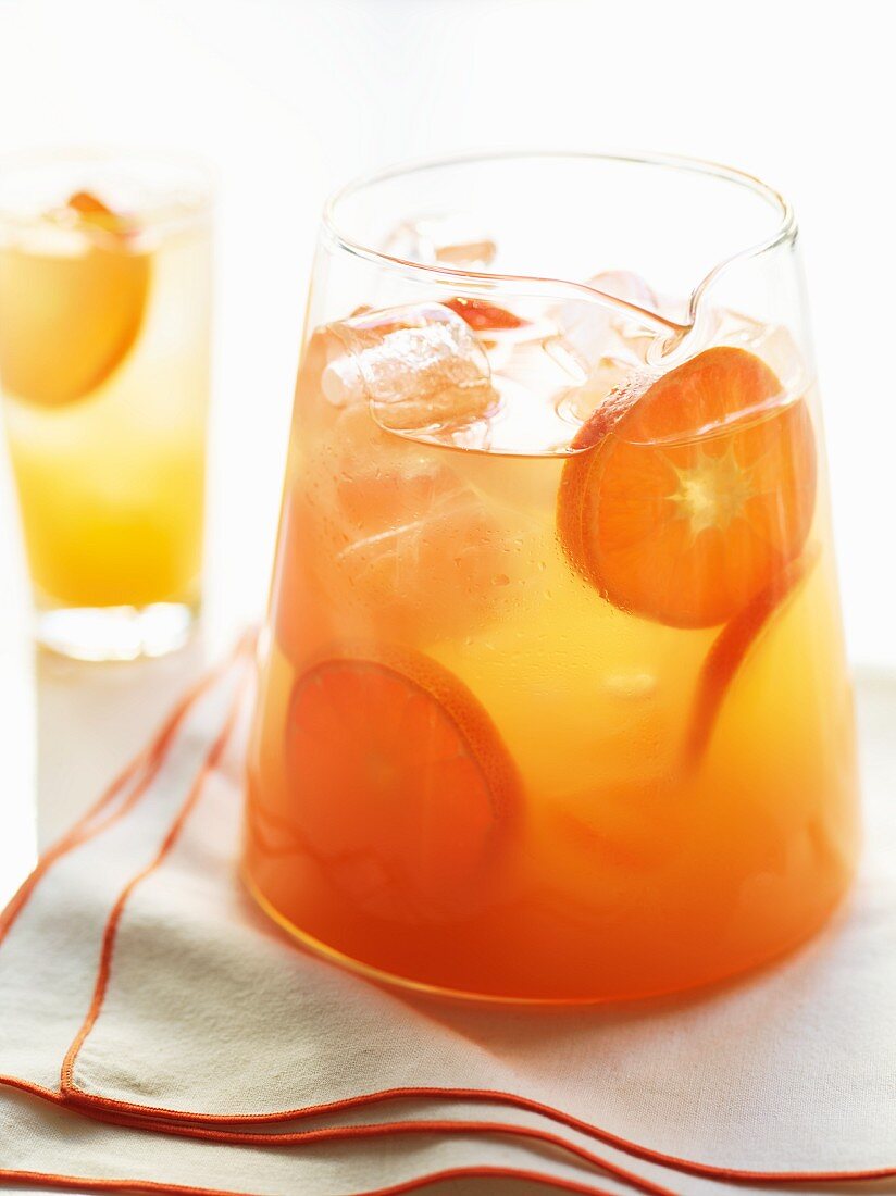 A jug of of fresh orange juice with ice cubes