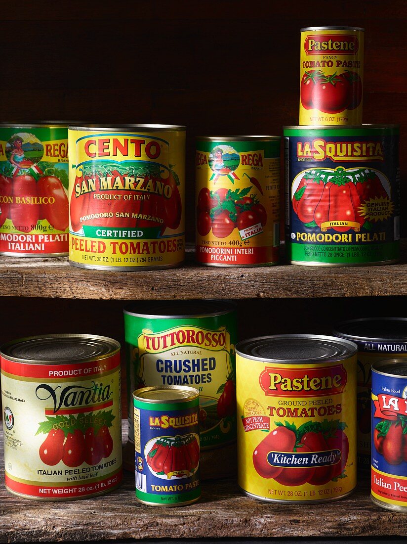 Various types of tinned tomatoes on a wooden shelf