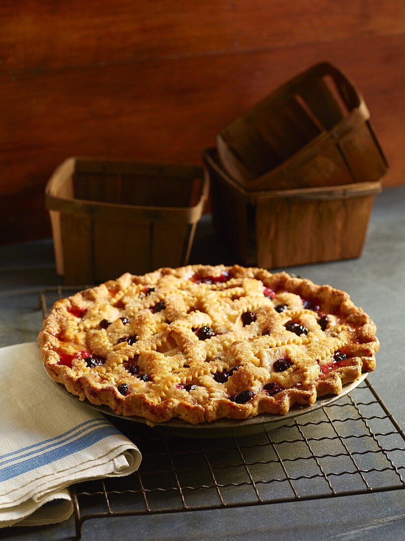 A whole berry pie with a lattice crust on a cooling rack