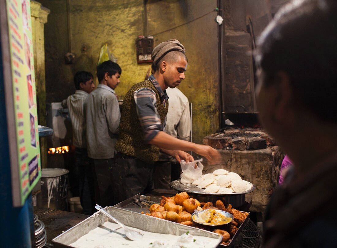 Traditionelles Street Food (Reisfladen und Aloo Tikki Bratkartoffeln) bei einem Straßenstand in Varanasi, Indien