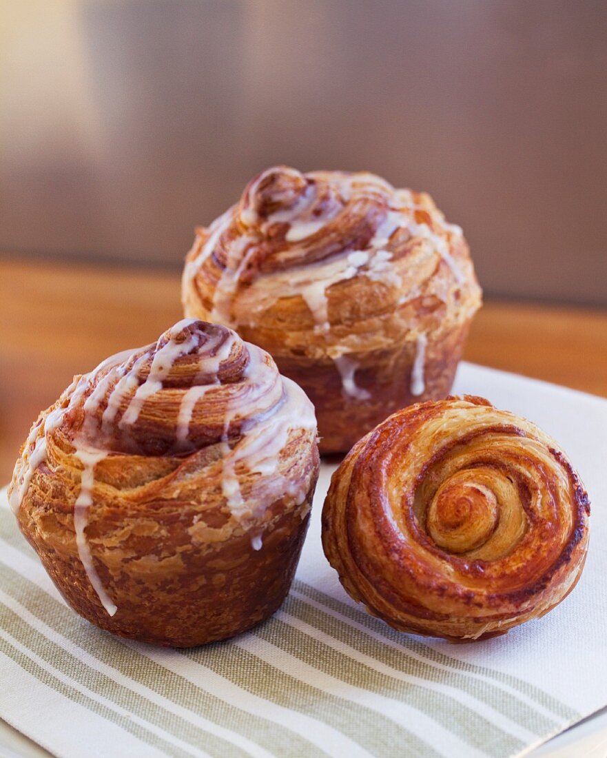 Three cinnamon buns with icing sugar on a napkin