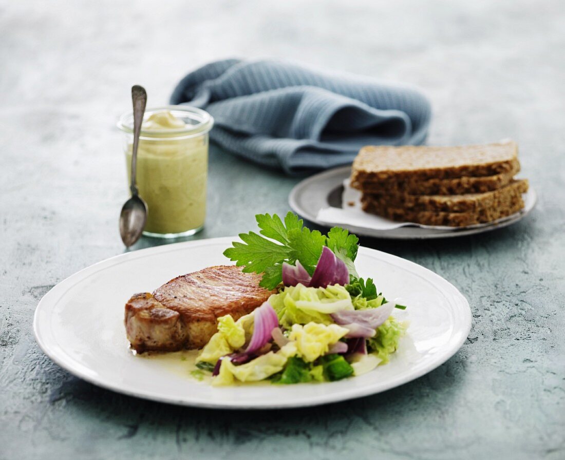 Pork chop with a mixed leaf salad served with wholemeal bread