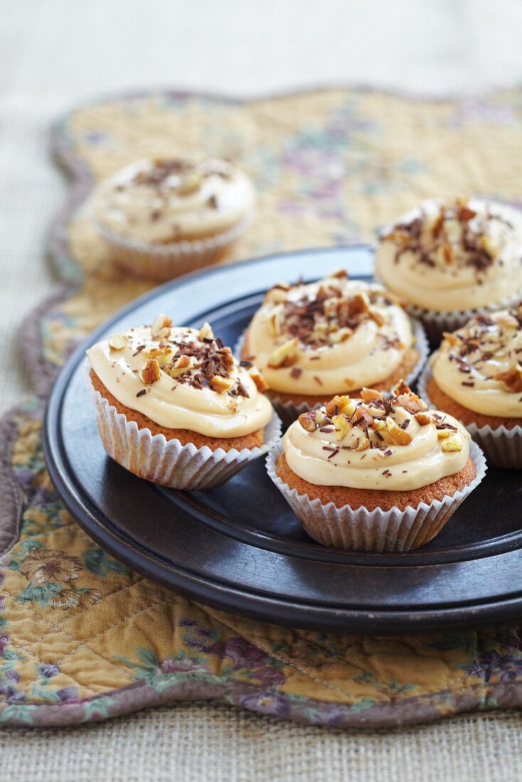 Fairy cakes decorated with frosting, walnuts and chocolate curls