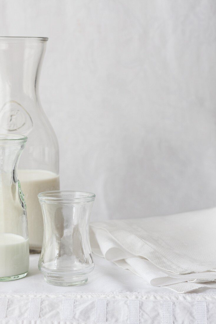 Various types of milk in different bottles on a white tablecloth