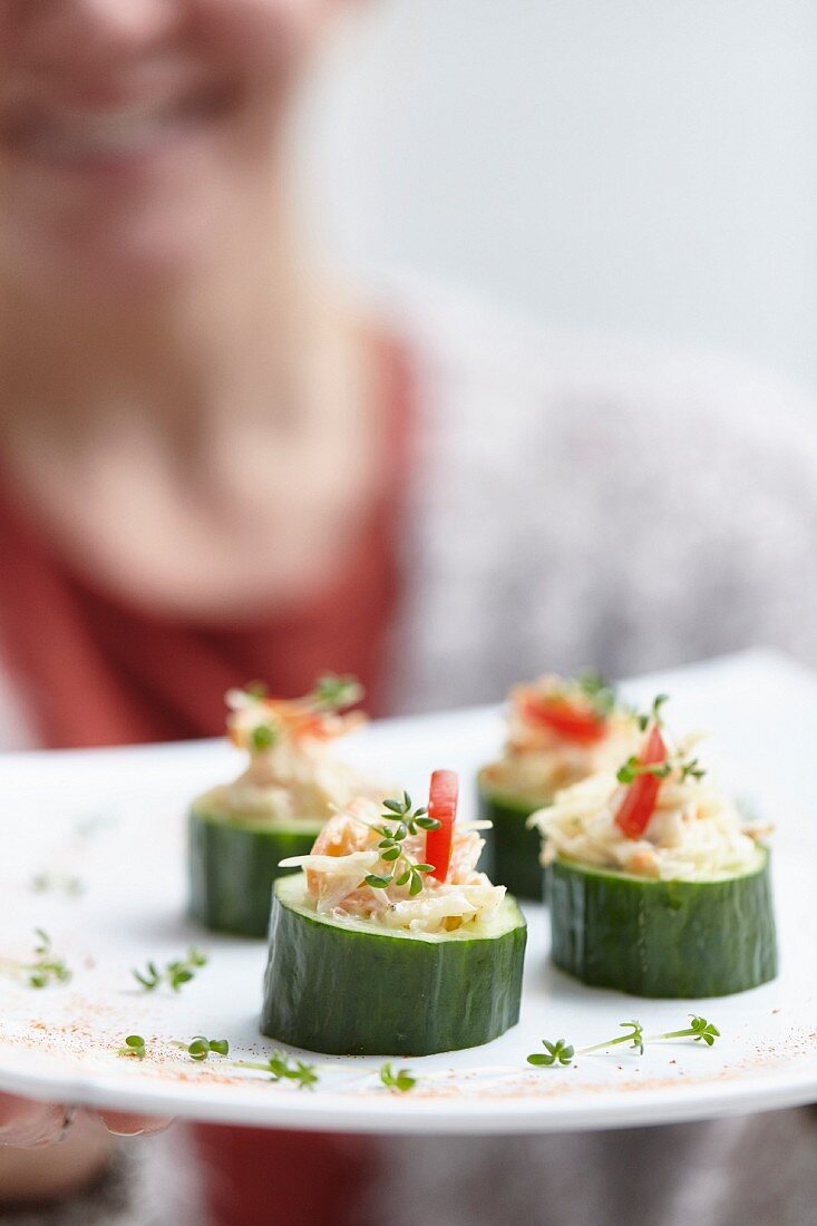 Woman Placing Platter of Cucumber Appetizers on Table