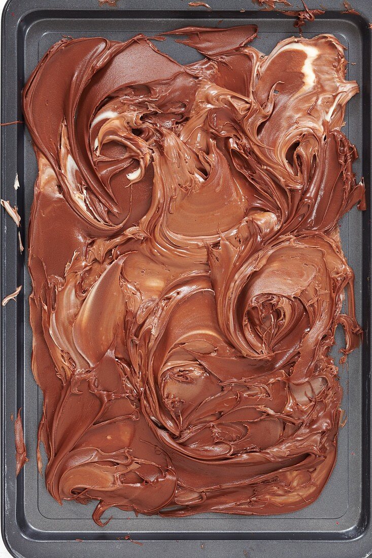 Geschmolzene Vollmilchschokolade & dunkle Schokolade auf Backblech vermischt