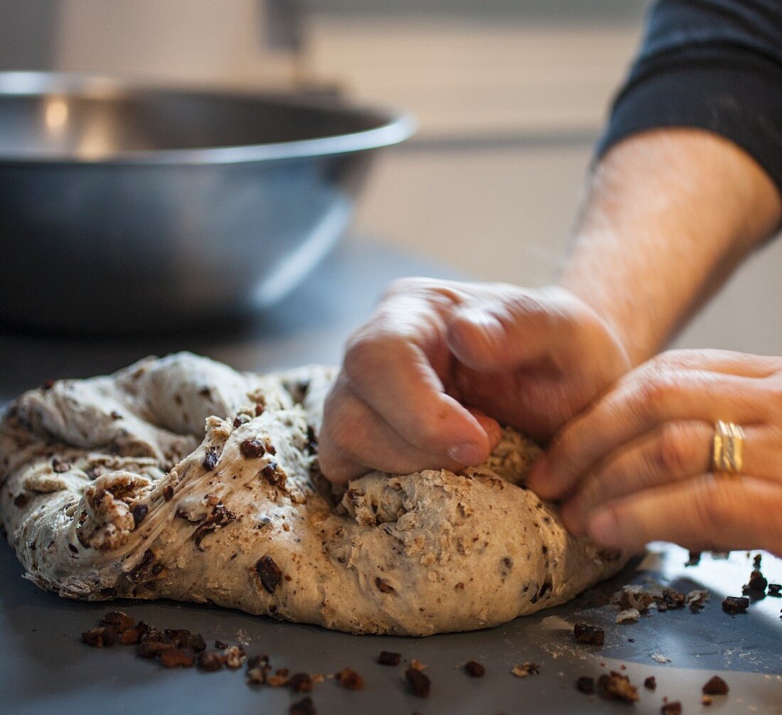 Hands kneading bread dough to make walnut and raisin bread (Italy)
