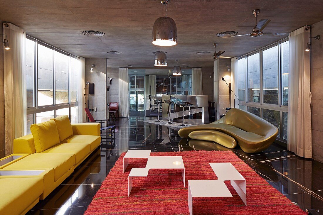 Delicate coffee table in white-painted metal on red rug, yellow sofa and golden sofa by Zaha Hadid