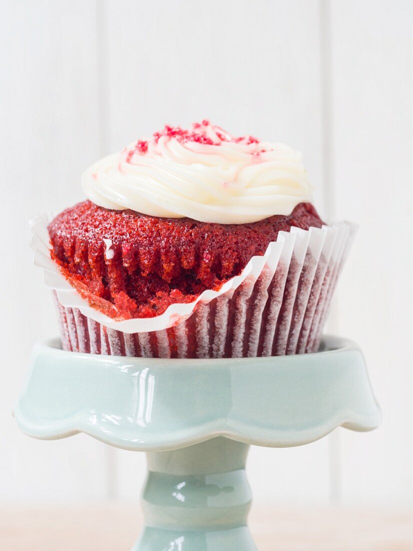 A Red Velvet cupcakes with white frosting on a cake stand (close-up)