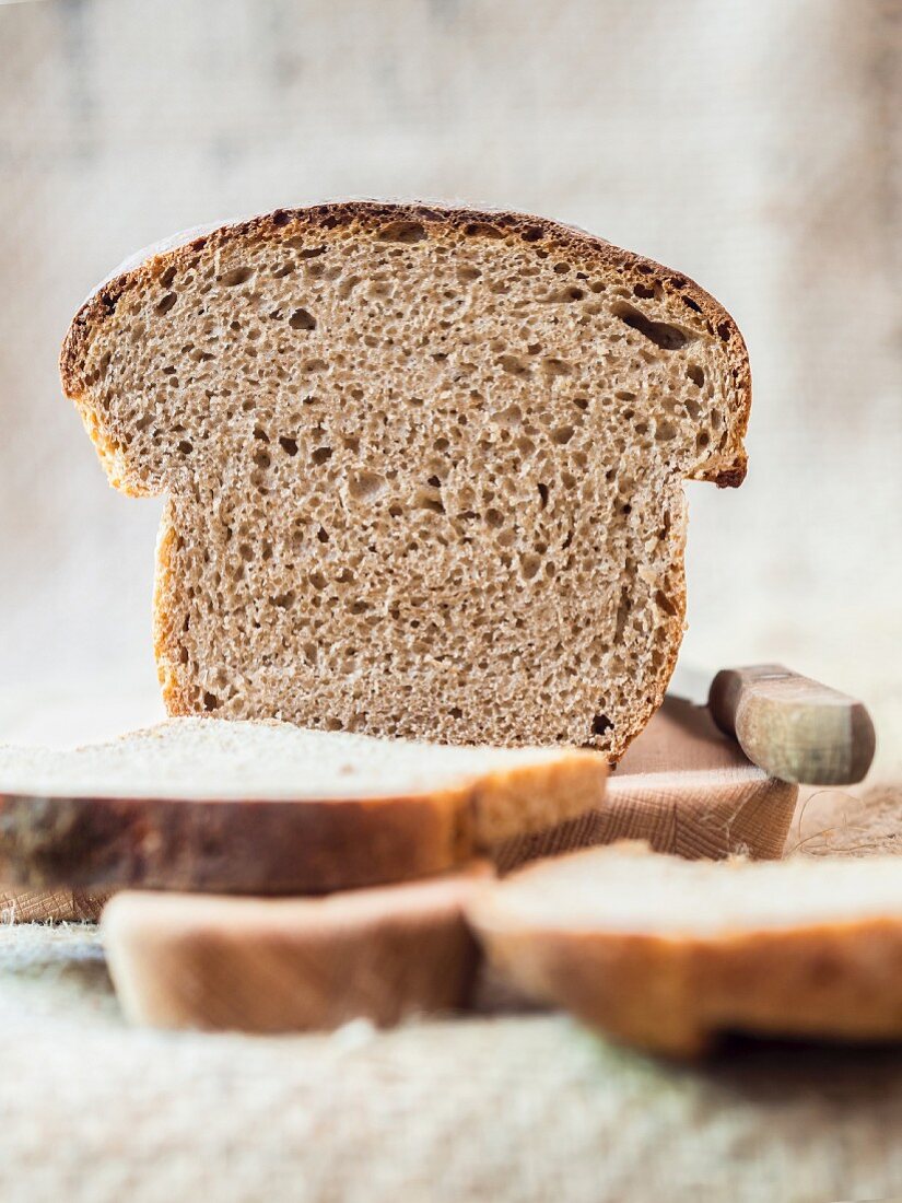 Brotscheiben von hausgemachtem Sauerteigbrot auf Schneidebrett