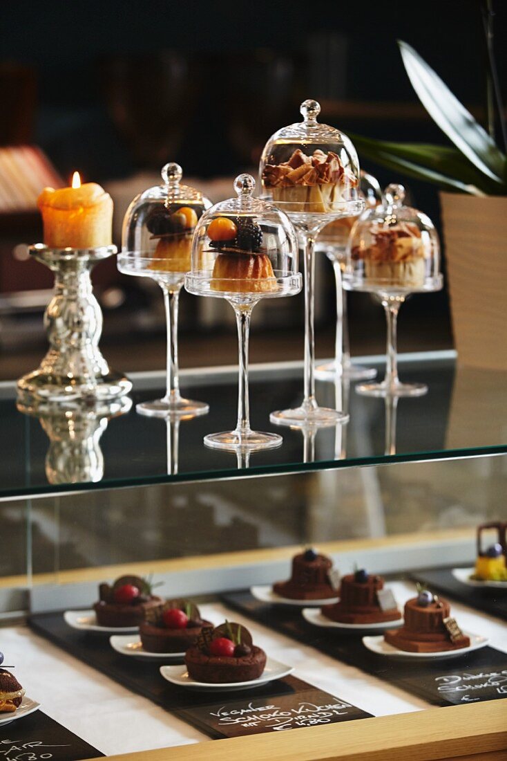 Desserts under mini glass cloches on a bar in a restaurant